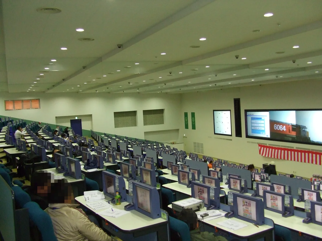 Archive photograph of the USS Ryutsu auction bidding hall, with rows of buyer desks and vehicle display screens